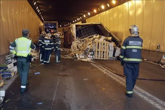 Unos bomberos trabajan en el t&uacute;nel de acceso a Algeciras (C&aacute;diz) donde esta ma&ntilde;ana ha fallecido una persona en un accidente de tr&aacute;fico cuando un cami&oacute;n de origen marroqu&iacute; que transportaba fruta y verdura se sali&oacute; de la v&iacute;a, volc&oacute; e impact&oacute; contra cuatro veh&iacute;culos uno de los cu&aacute;les qued&oacute; bajo el remolque. EFE