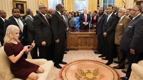 Counselor to the President Kellyanne Conway (L) checks her phone after taking a photo as US President Donald Trump and leaders of historically black universities and colleges pose for a group photo in the Oval Office of the White House before a meeting with US Vice President Mike Pence February 27, 2017 in Washington, DC. / AFP PHOTO / Brendan Smialowski